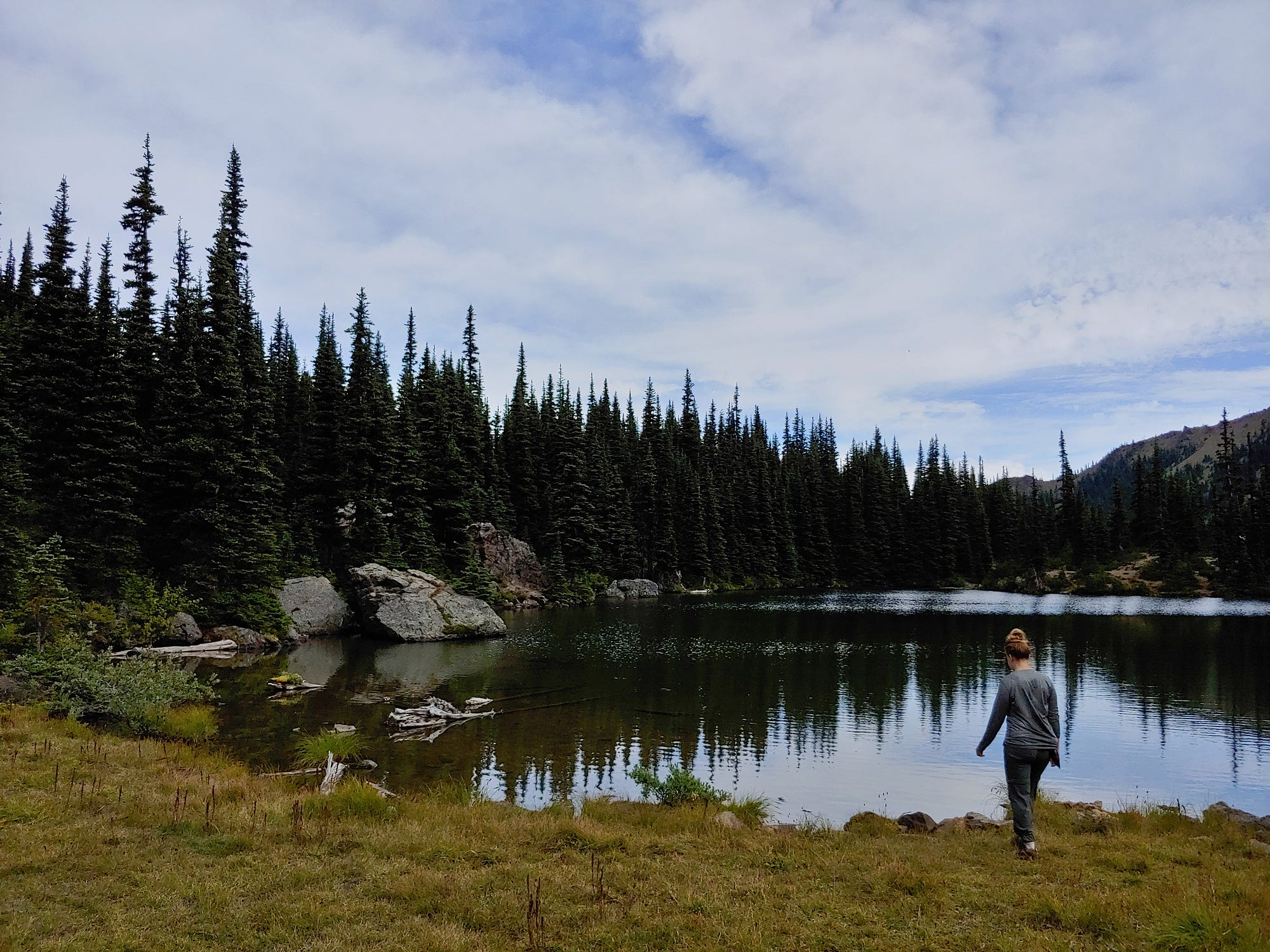 A hiker approaches the shore of Silver Lake in Olympic National Forest.
