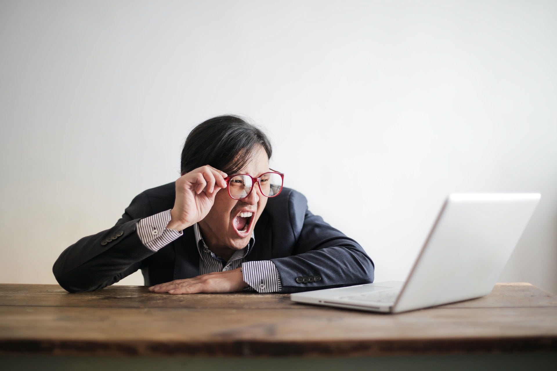 A worker looking at his laptop in angry disbelief.