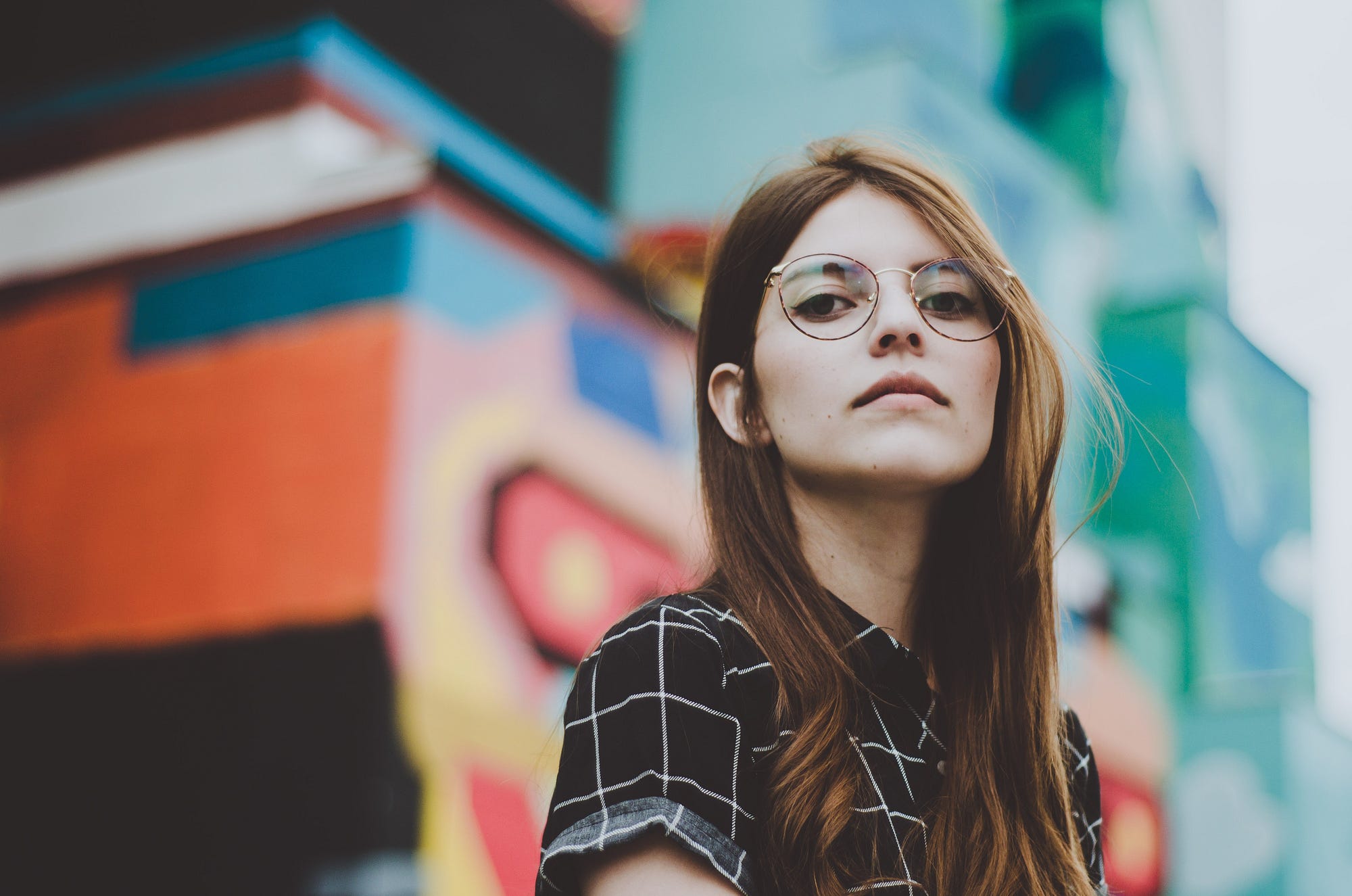 Image of a white woman looking serious against a colorful background.