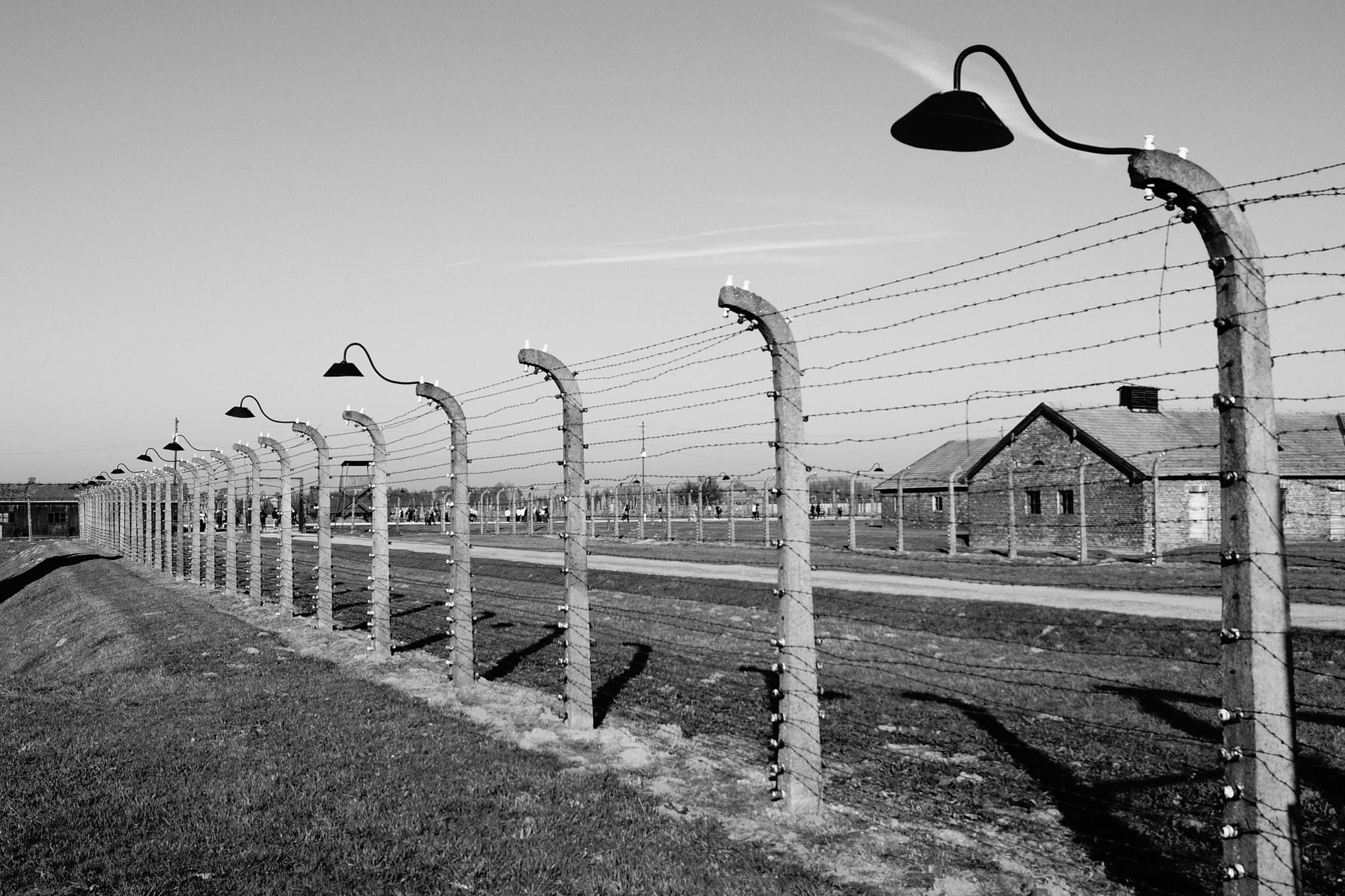 A black an white photo of a barbed wire fence around Auschwitz concentration camp