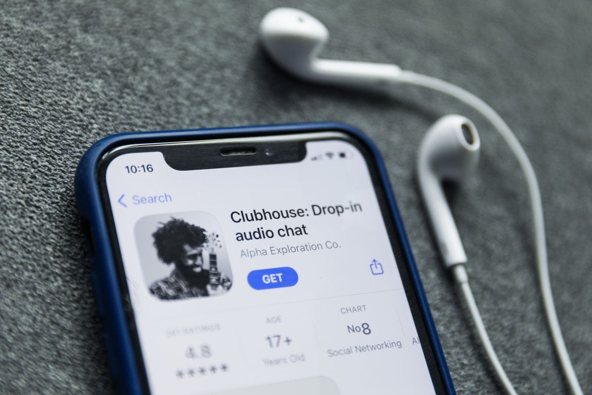 iPhone with AppStore opened in the main page of the app Clubhouse. Wired earphones next to the iPhone