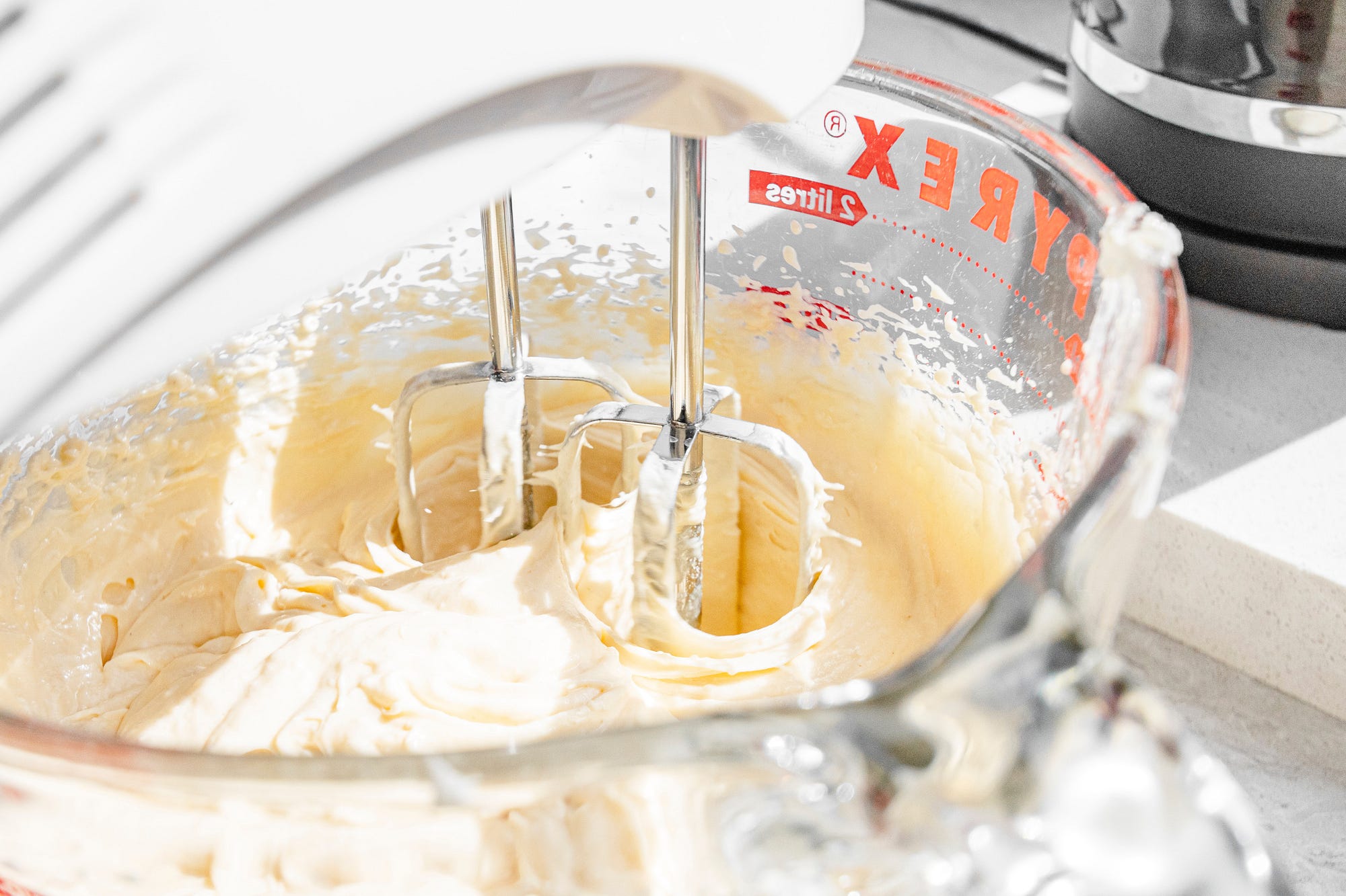 Cake mixture in a mixing bowl with an electric mixer.