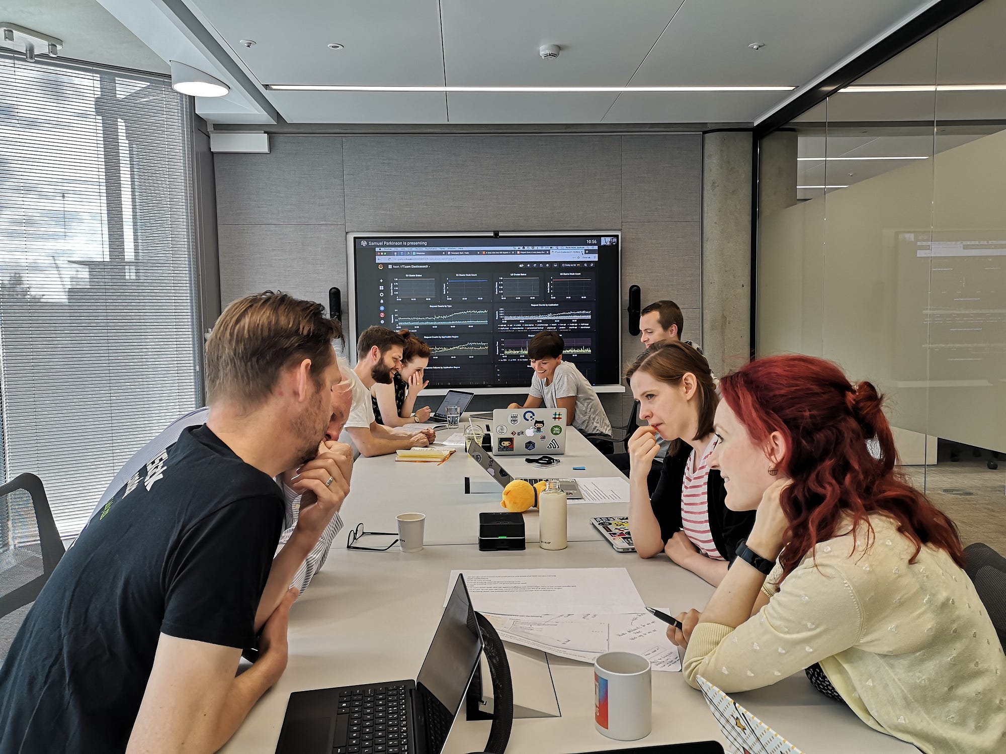 The engineering team working together to resolve a pratice incident with a dashboard of graphs in the background.