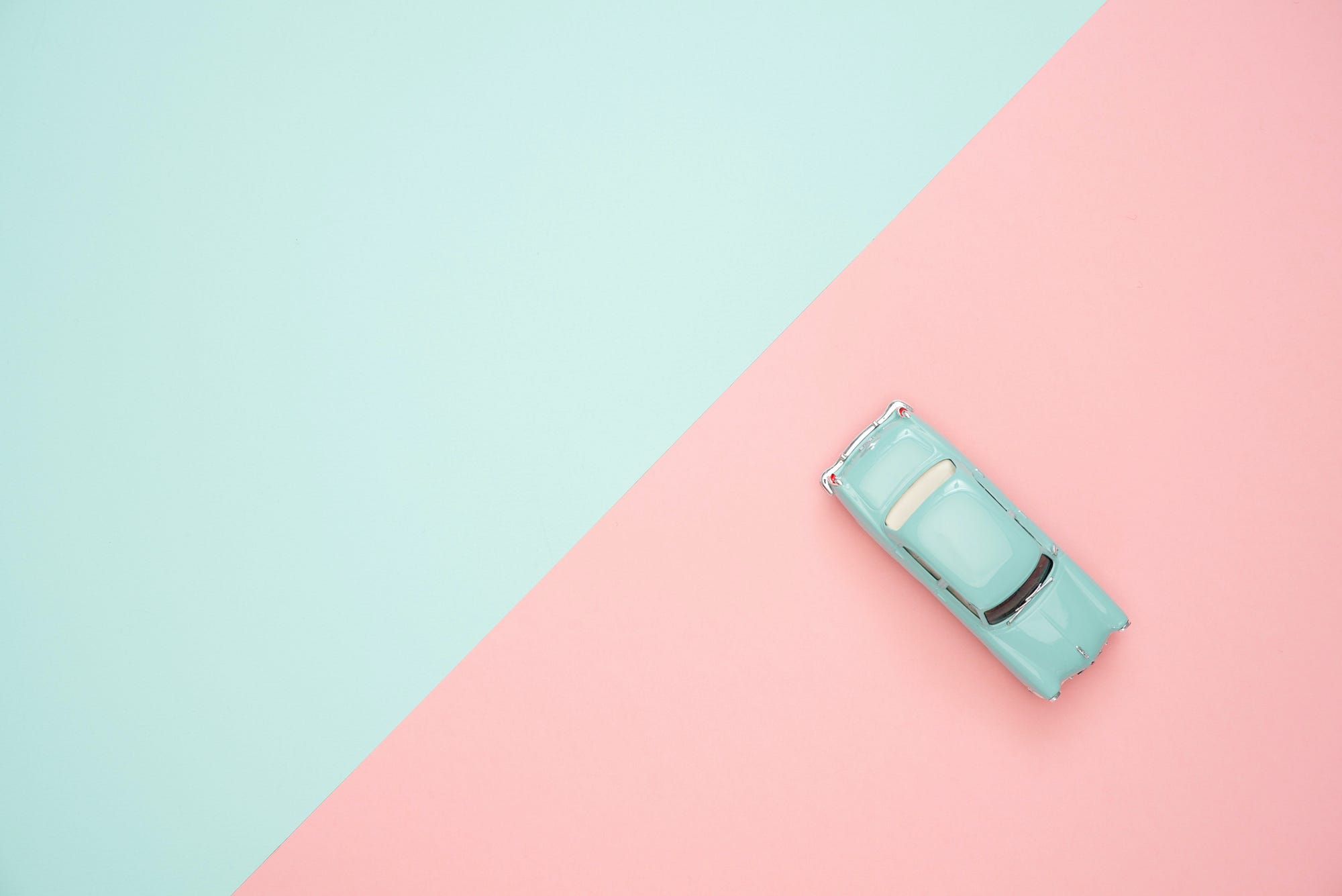 Divide between blue and pink sides of a photo, with a blue toy car on the pink side