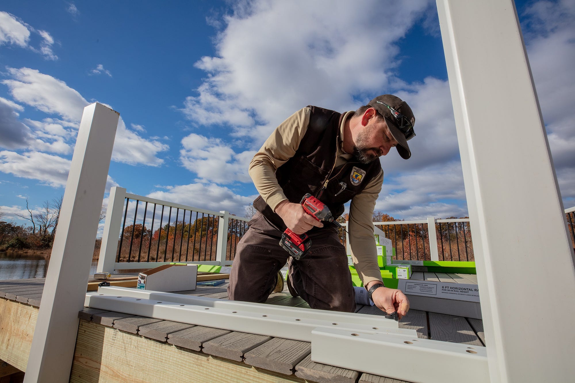 man in FWS uniform kneeling on wooden platform holding electric screwdriver or drill