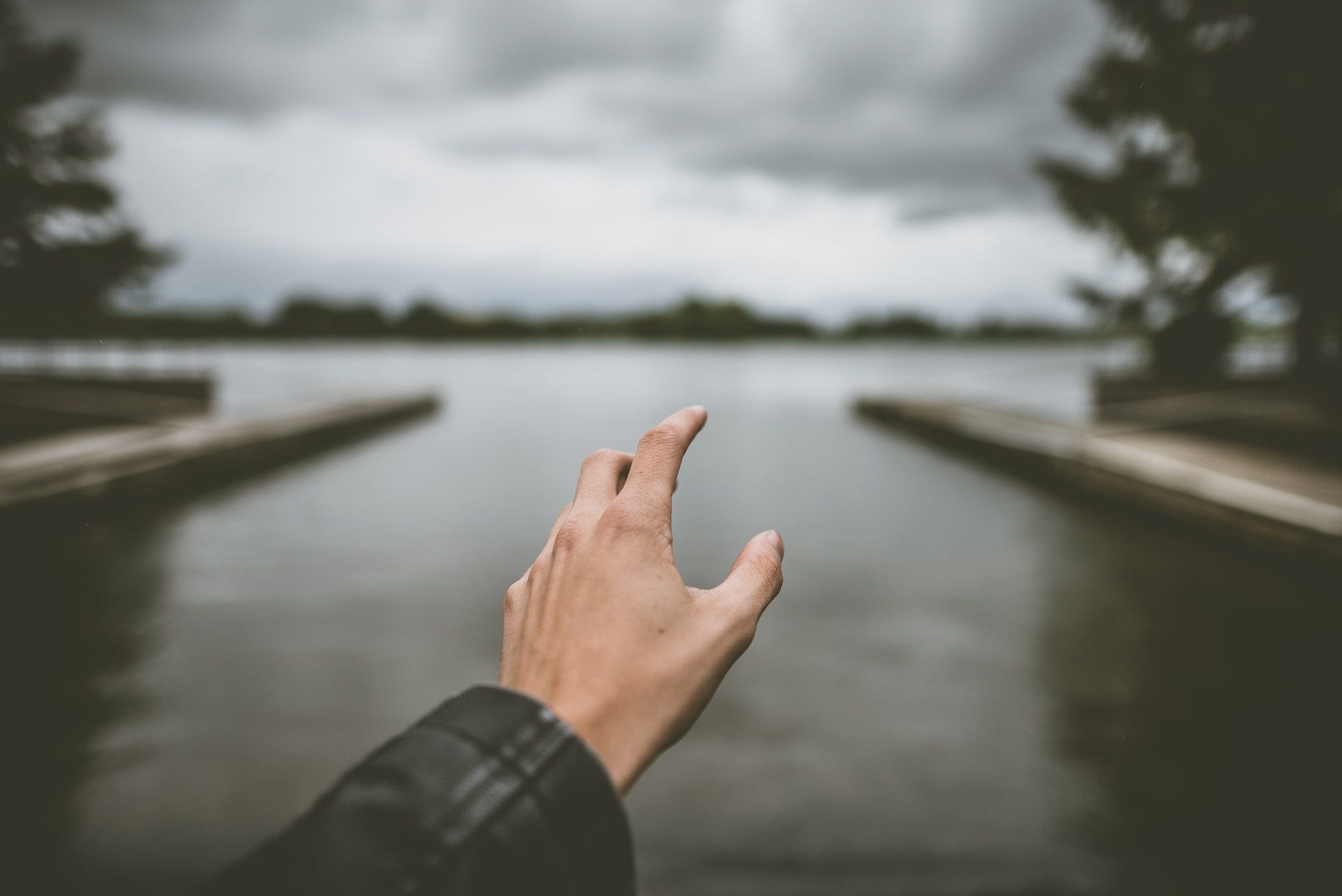 A man’s hand reaching to a lake