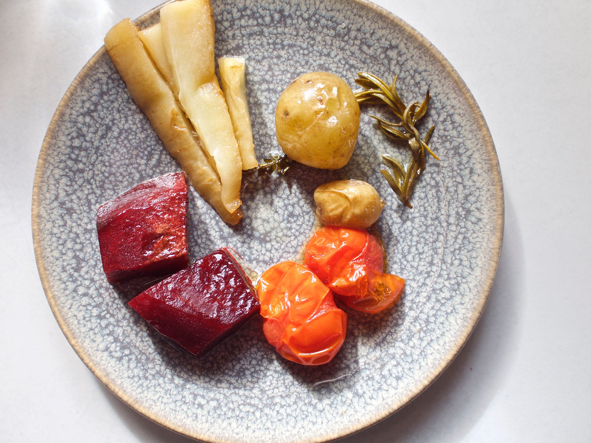 A plated of roasted parsnips, red beets, withered confited tomatoes, potatoes, and thyme.