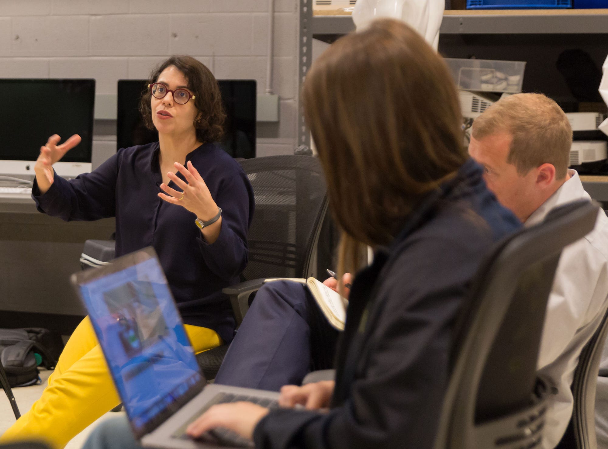 A UT engineering professor sits with fine arts and engineering students who are designing a virtual reality game about Texas.