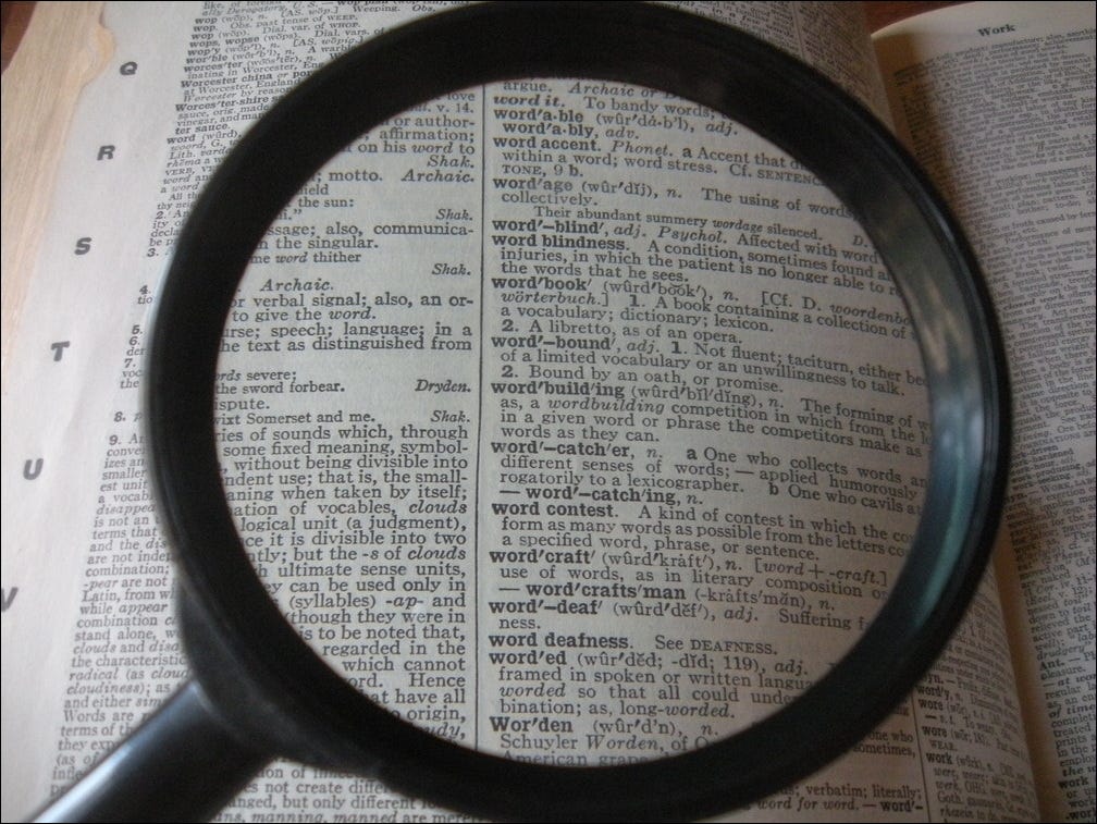 A magnifying glass focusing on a page in the dictionary