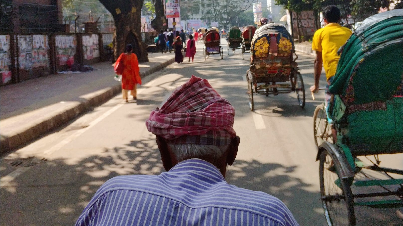 A back shot of an aging rickshaw driver in Dhaka