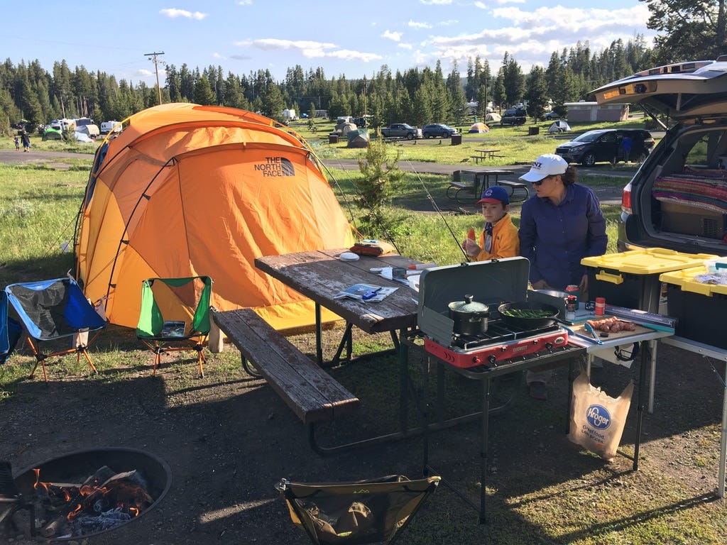 An orange tent and people camping in Yellowstone