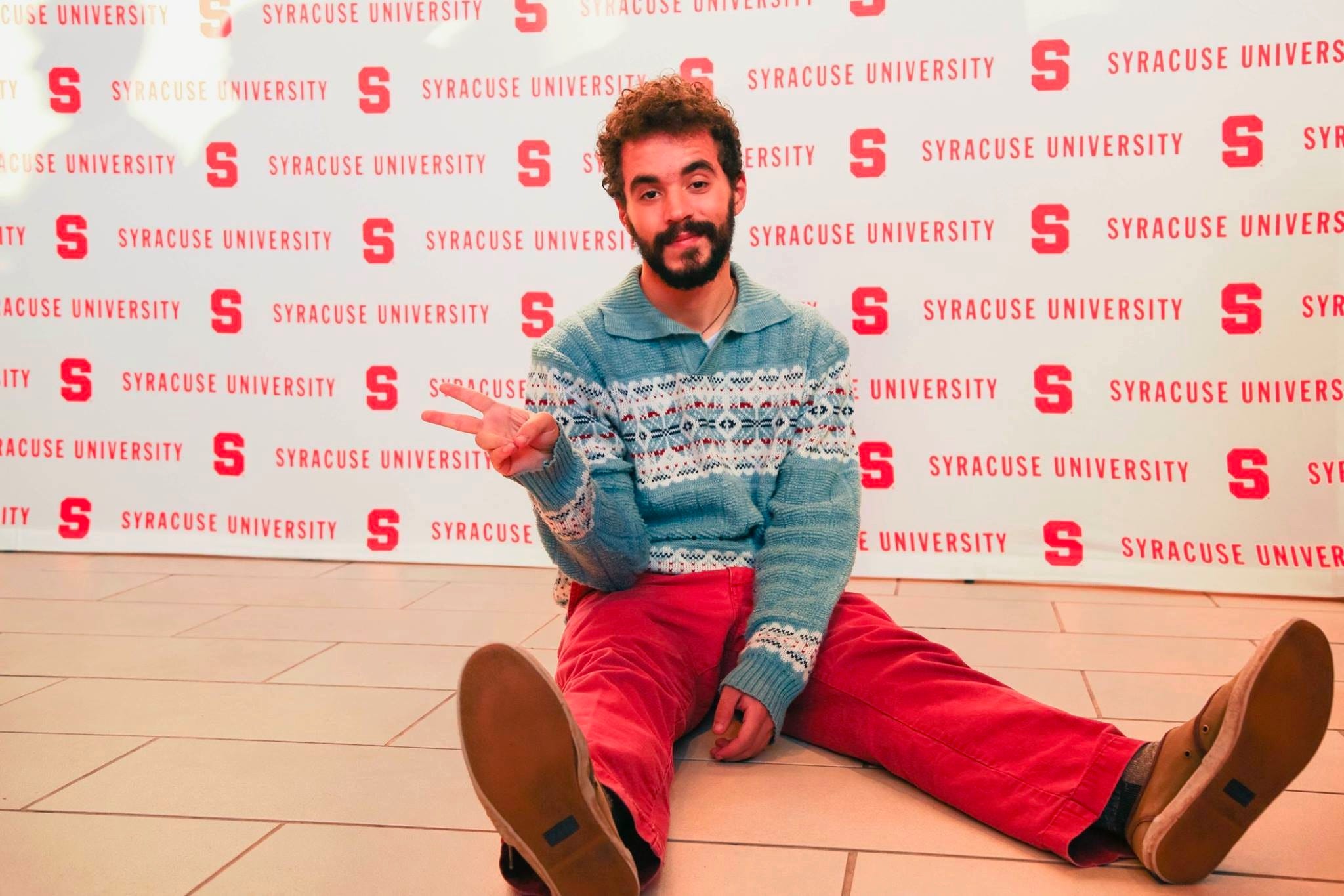 man sitting on floor throwing up a peace sign