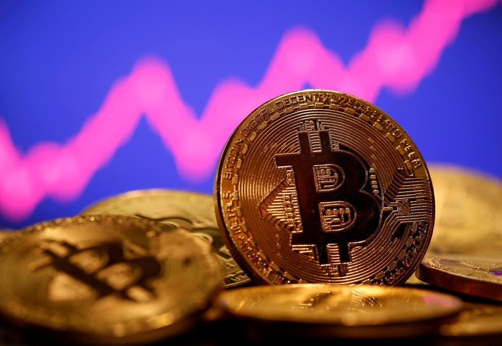 Stock photo of Bitcoin coins in front of a rising stock ticker.