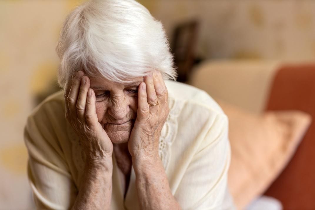 A senior woman with her hands on her face