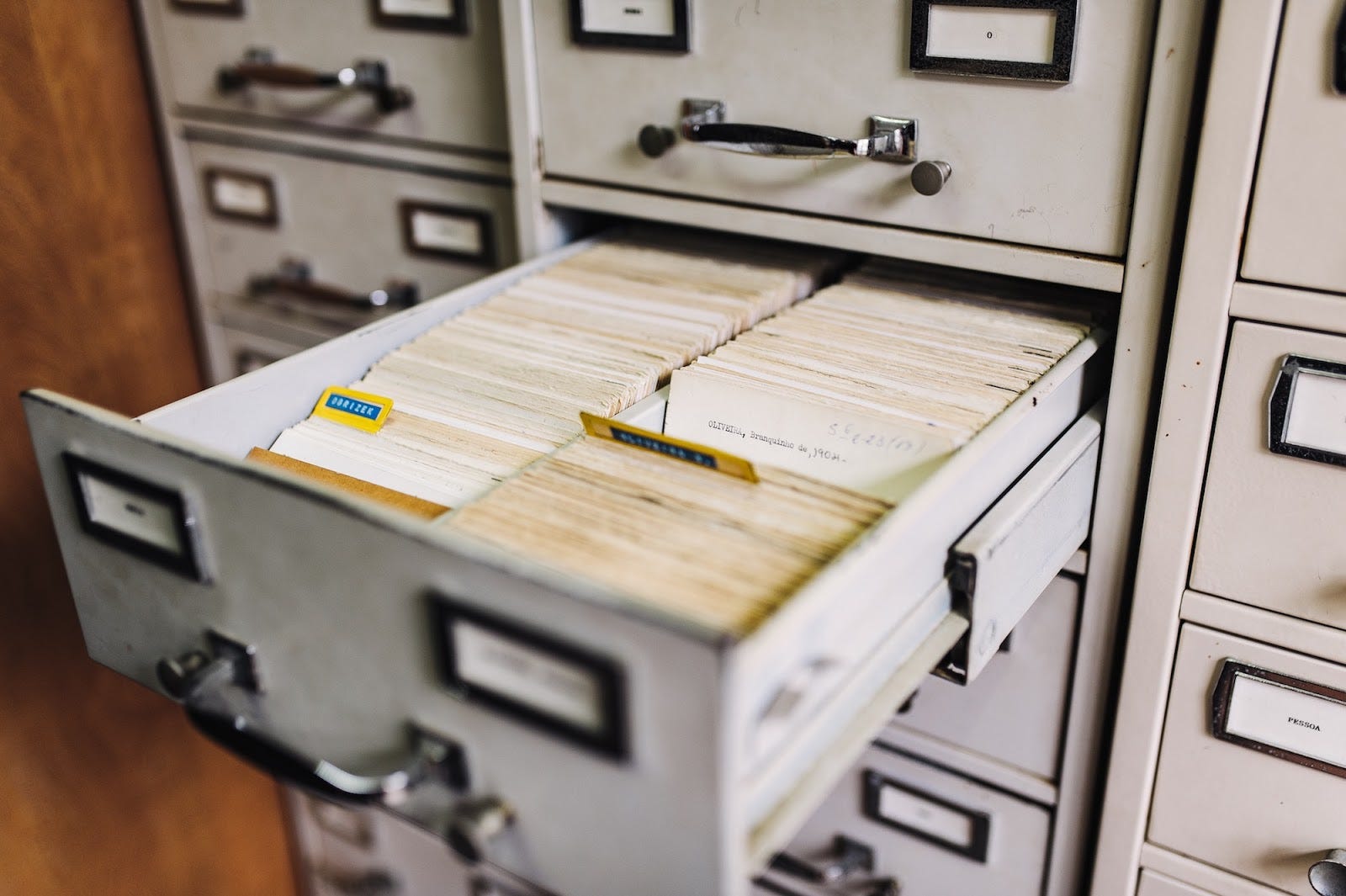 A filing cabinet with an open drawer with many index cards inside.