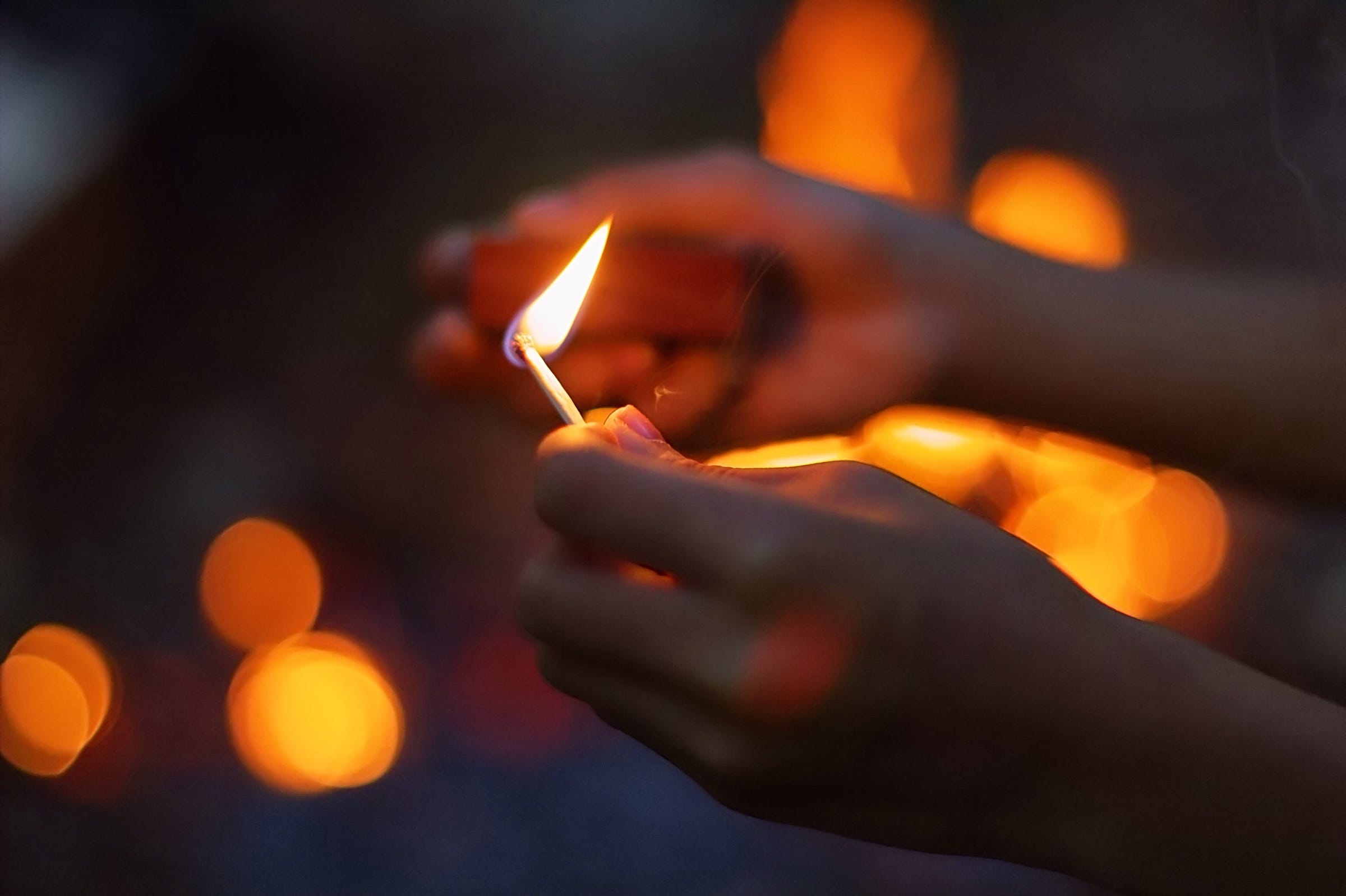Personโs hands holding a lit match.