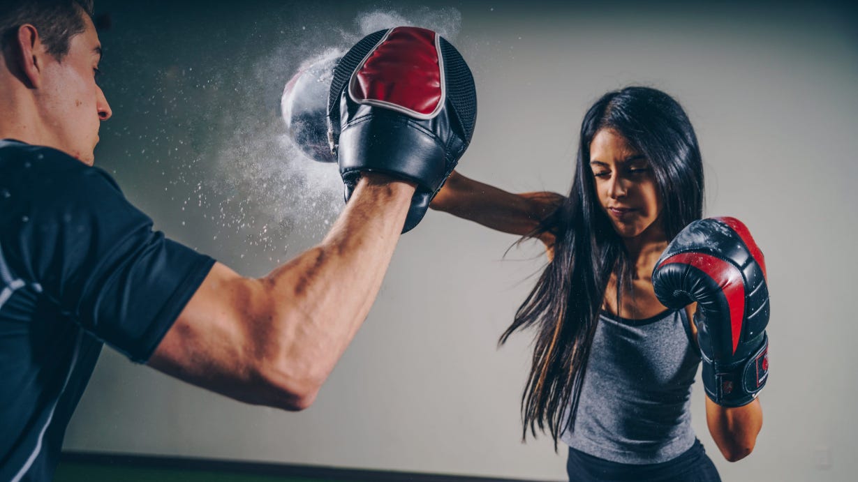 A woman hitting the pads in boxing training