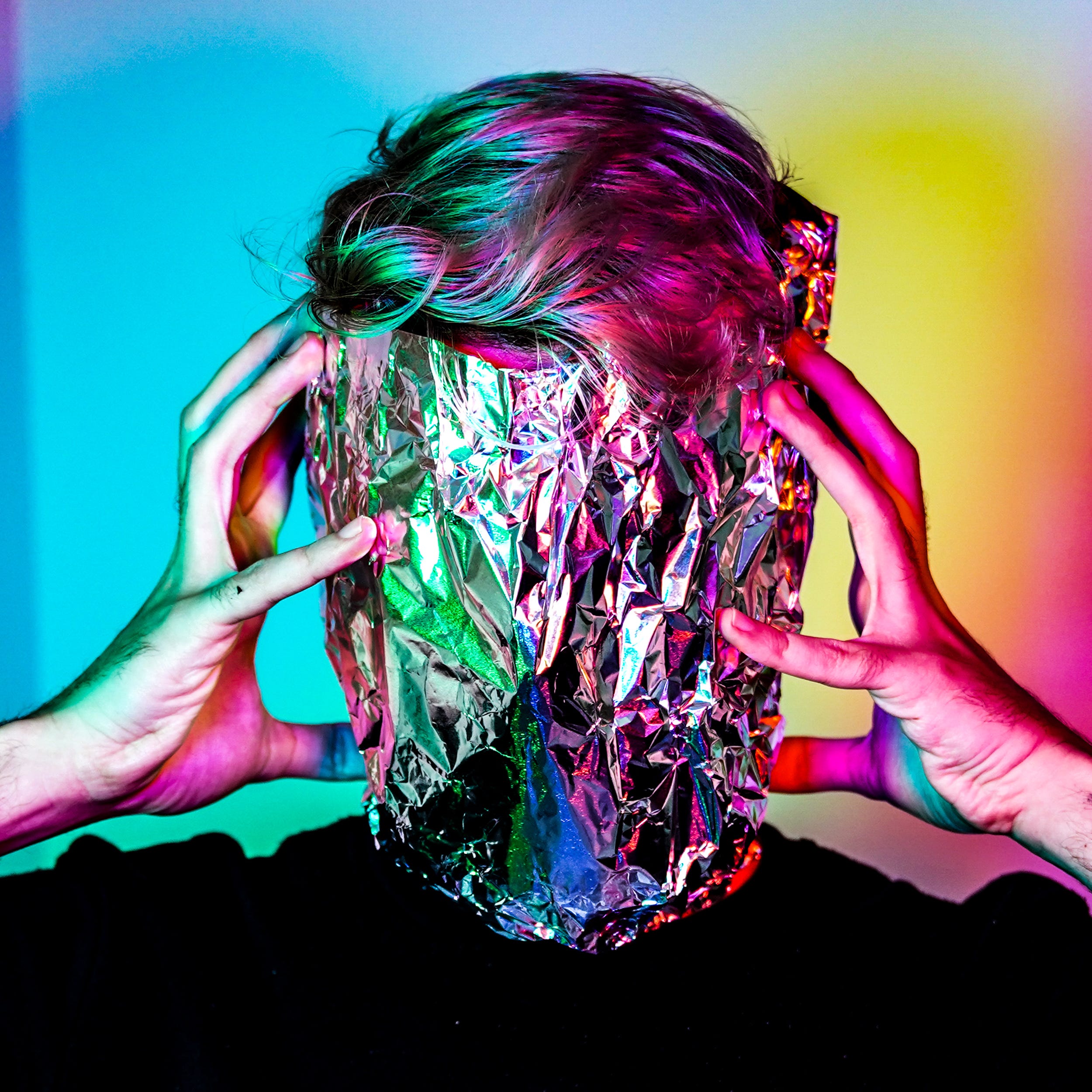 Beautiful and color filled image of a person with face covered and hands pressed to side of head as if a headache is forming.