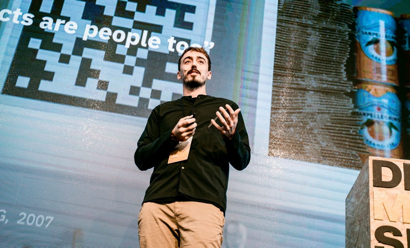 A man presenting on a stage in front of a large screen