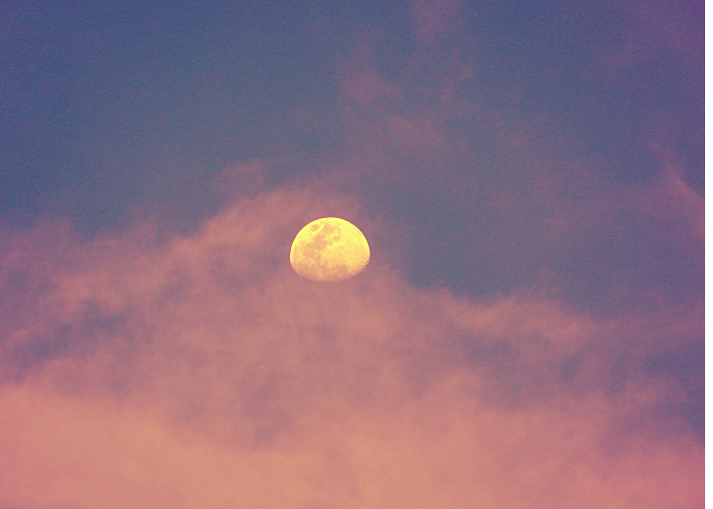 Light pink cloud surrounding an orange moon in the night sky