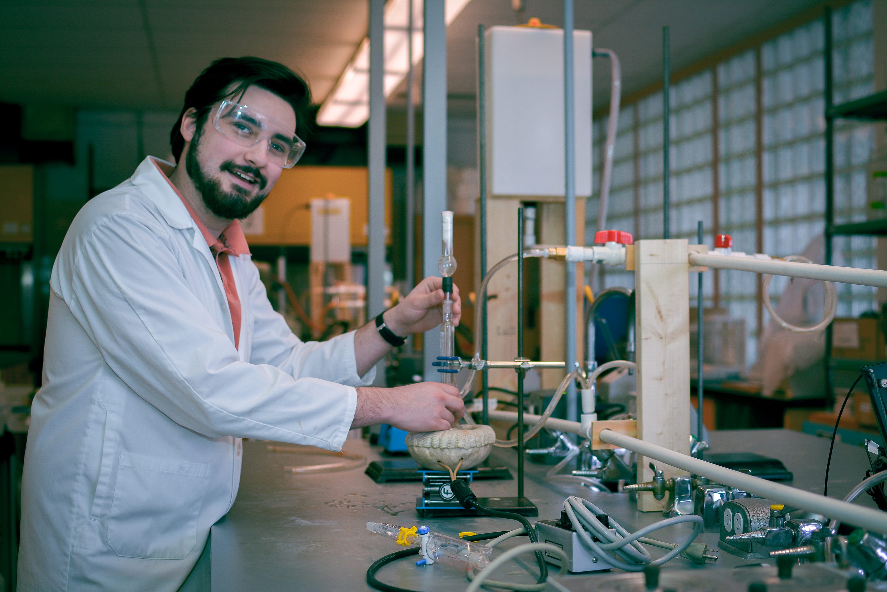 Young man in white lab coat adjusts tap