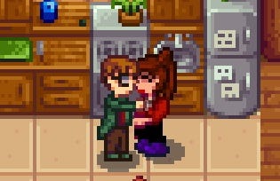 Two people, a man in a green coat and glasses and a woman with a brown ponytail and red shirt, kiss in a small rustic kitchen