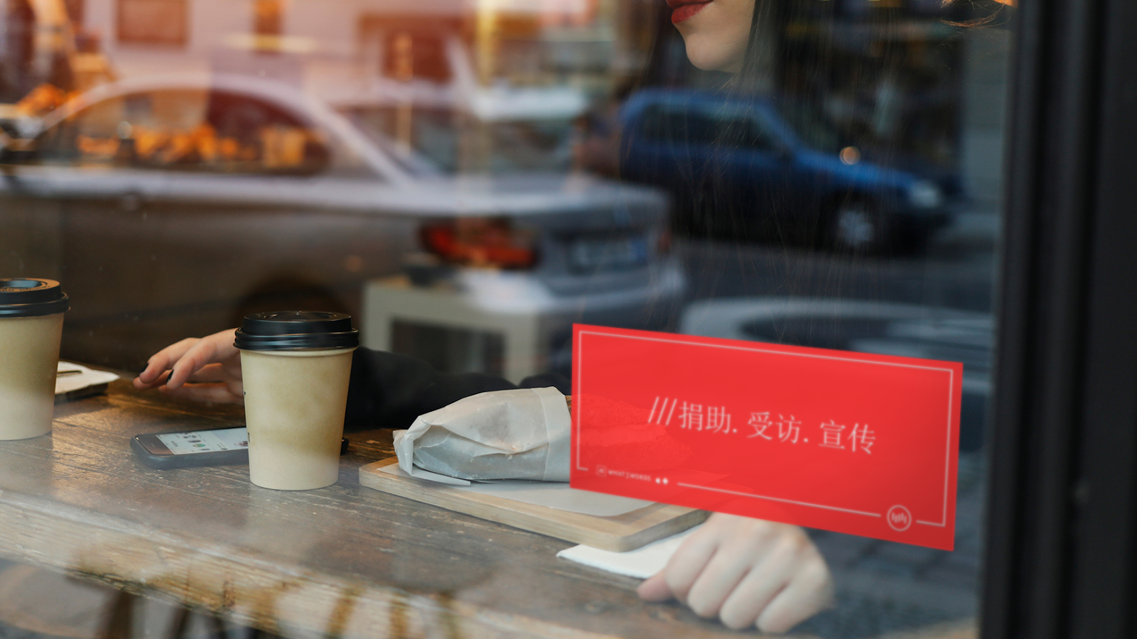 A cafe window with a red sign displaying a what3words address in Chinese