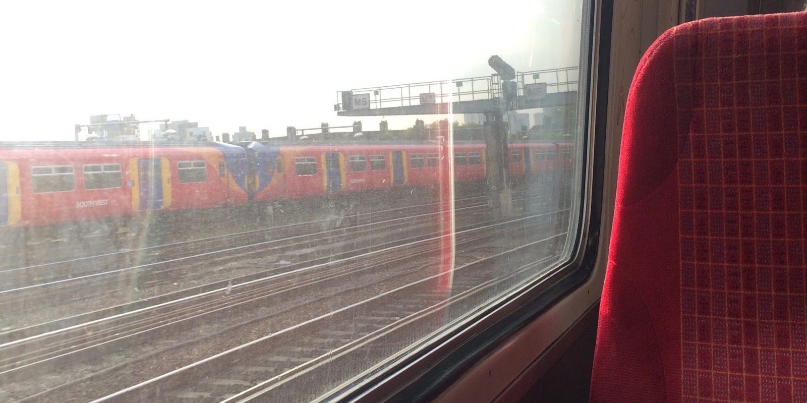 Train chair next to window with a view of another train moving.