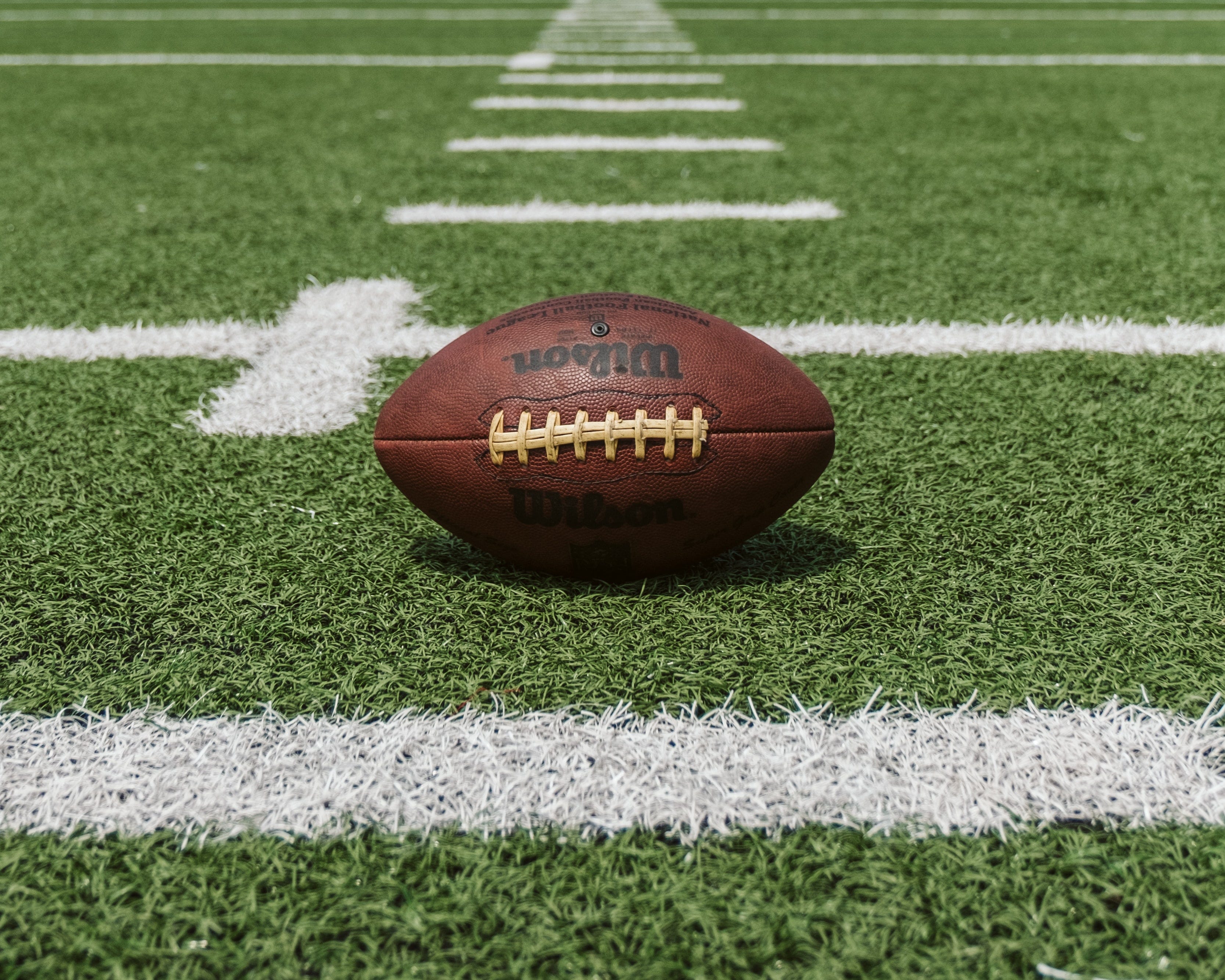 A closeup of a football on the grass of a football field