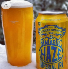 A beer can a glass of hazy IPA sit on the railing of a snow covered deck.