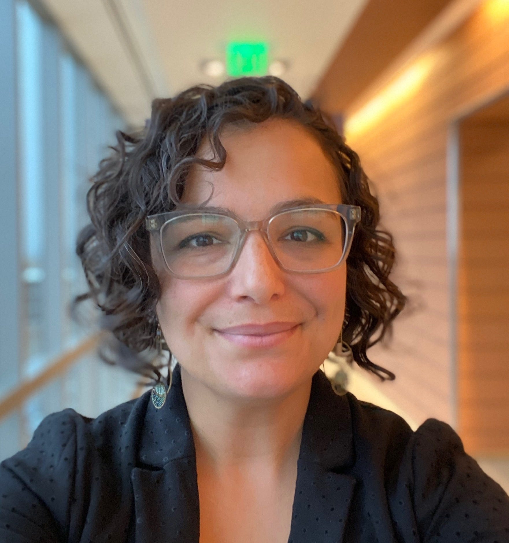 Woman with short dark brown hair and glasses.