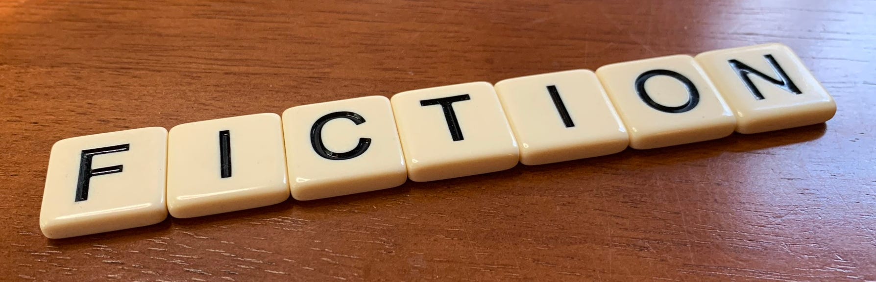 Letter tiles spelling out “Fiction” on a wooden desktop