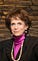 A headshot of Karen Lawrence smiling in front of a brown stone wall