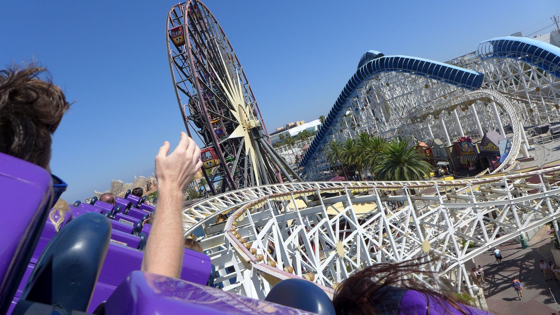 A human hand raised into the air as the human faces an unwinding roller coaster ride.