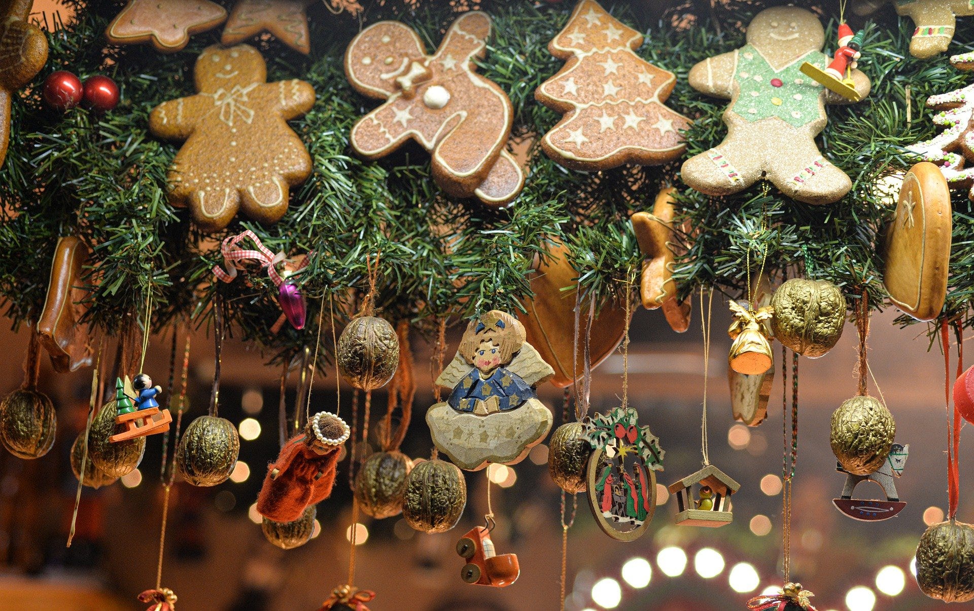 A bunch of Christmas decorations and gingerbread men are hanging in the air, onto a birghtly lit background.