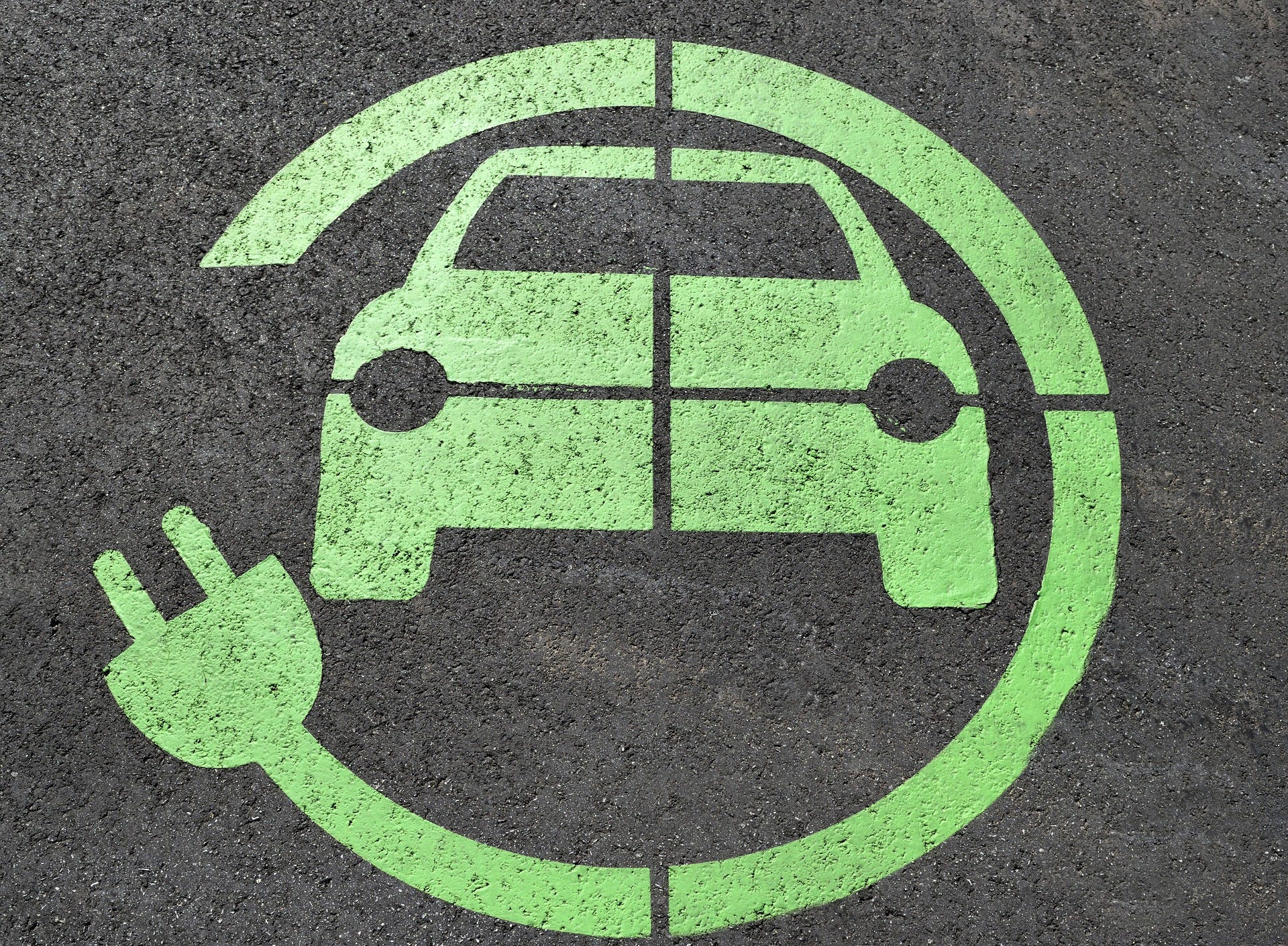 A green electric vehicle charging sign on a parking space