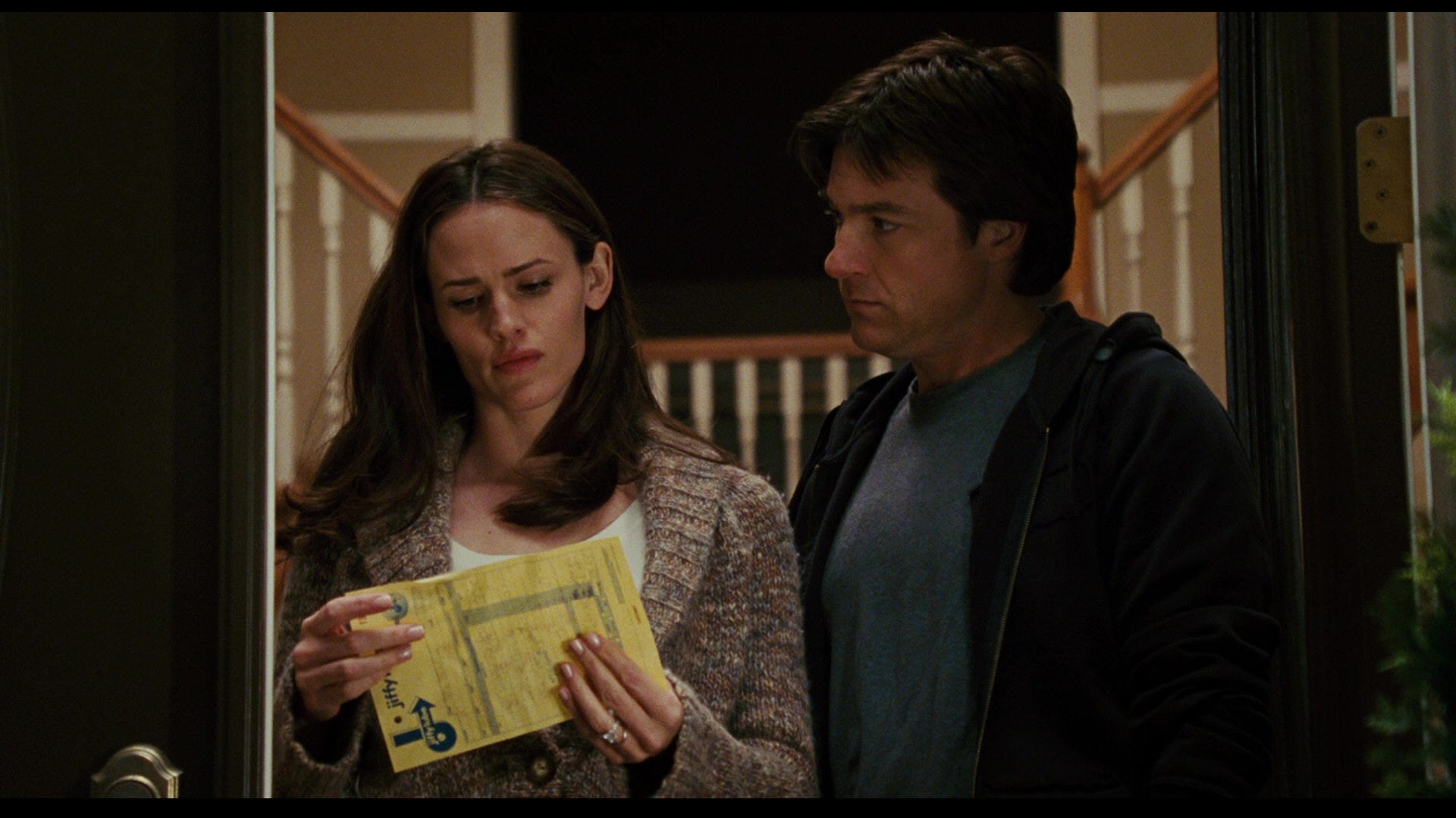 Jennifer Garner as Vanessa Loring holding a yellow paper in her hands as Jason Bateman as Mark Loring looks at her.