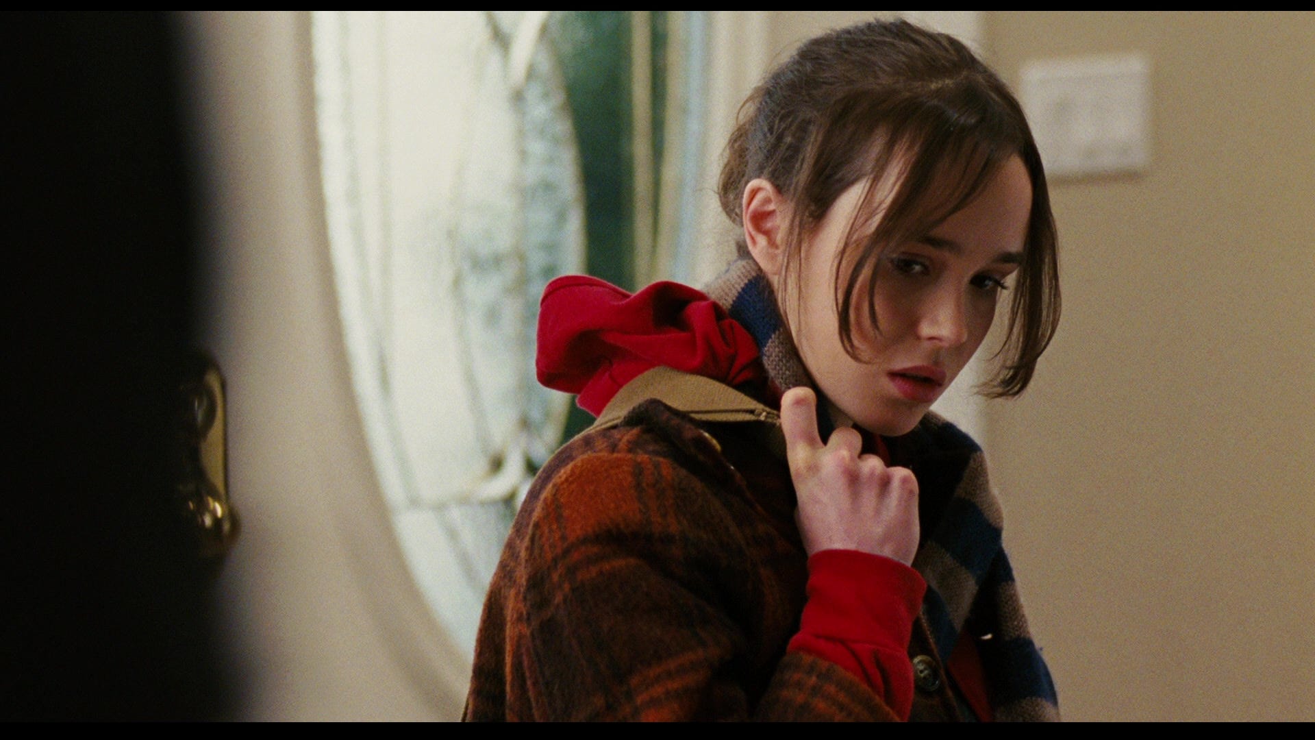 Elliot Page as Juno MacGuff standing in the foyer of a house.