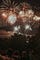 Multiple fireworks go off in front of a forest in the dark.