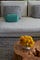 A grey sofa with teal pillows sitting on a grey rug.