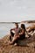 A man and woman sit next to a lake and gaze into each other’s eyes