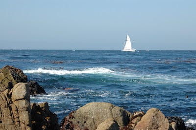 Monterey Bay waves with a sail boat in the distance.