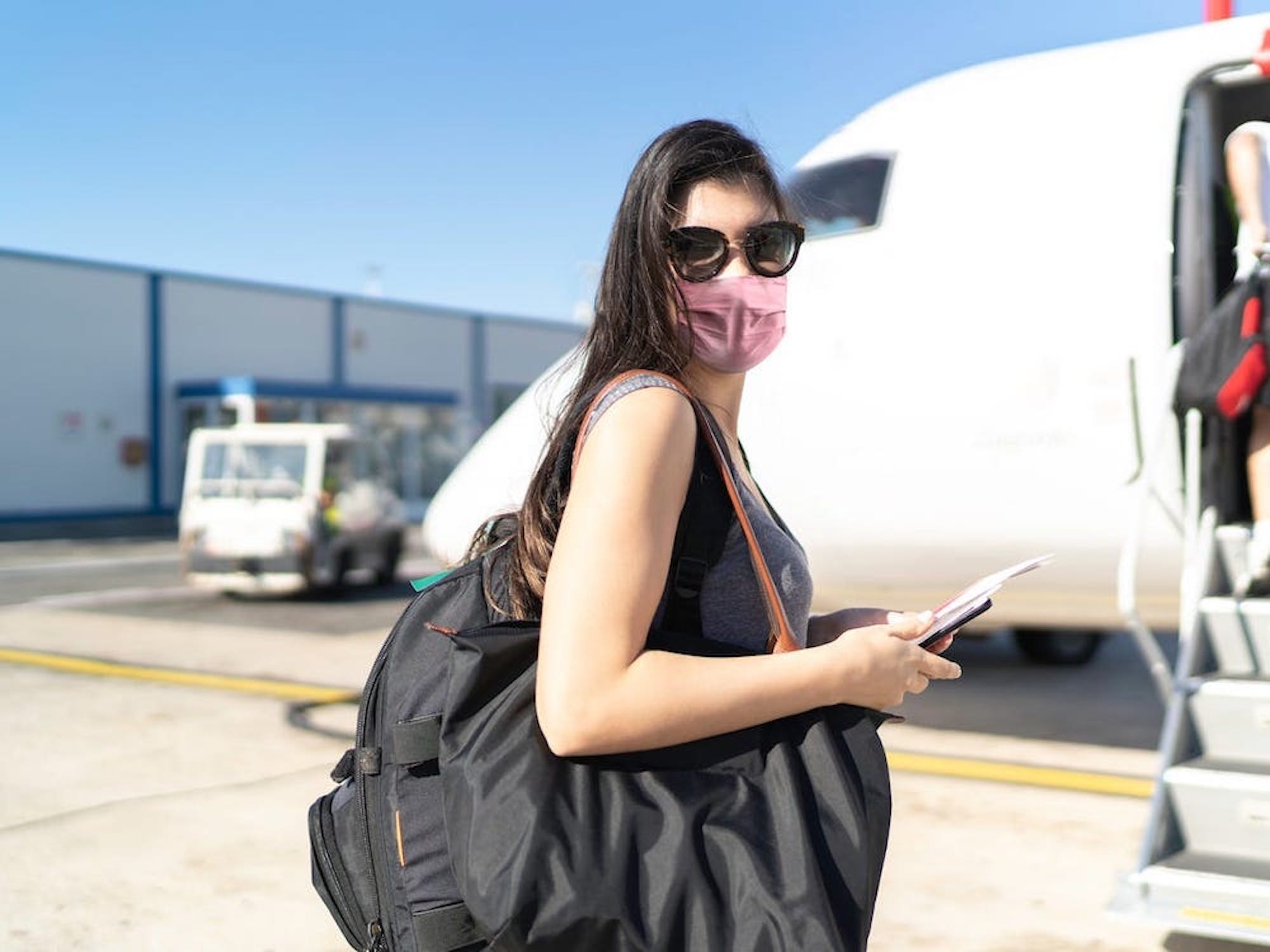 A masked traveler boards a plane.