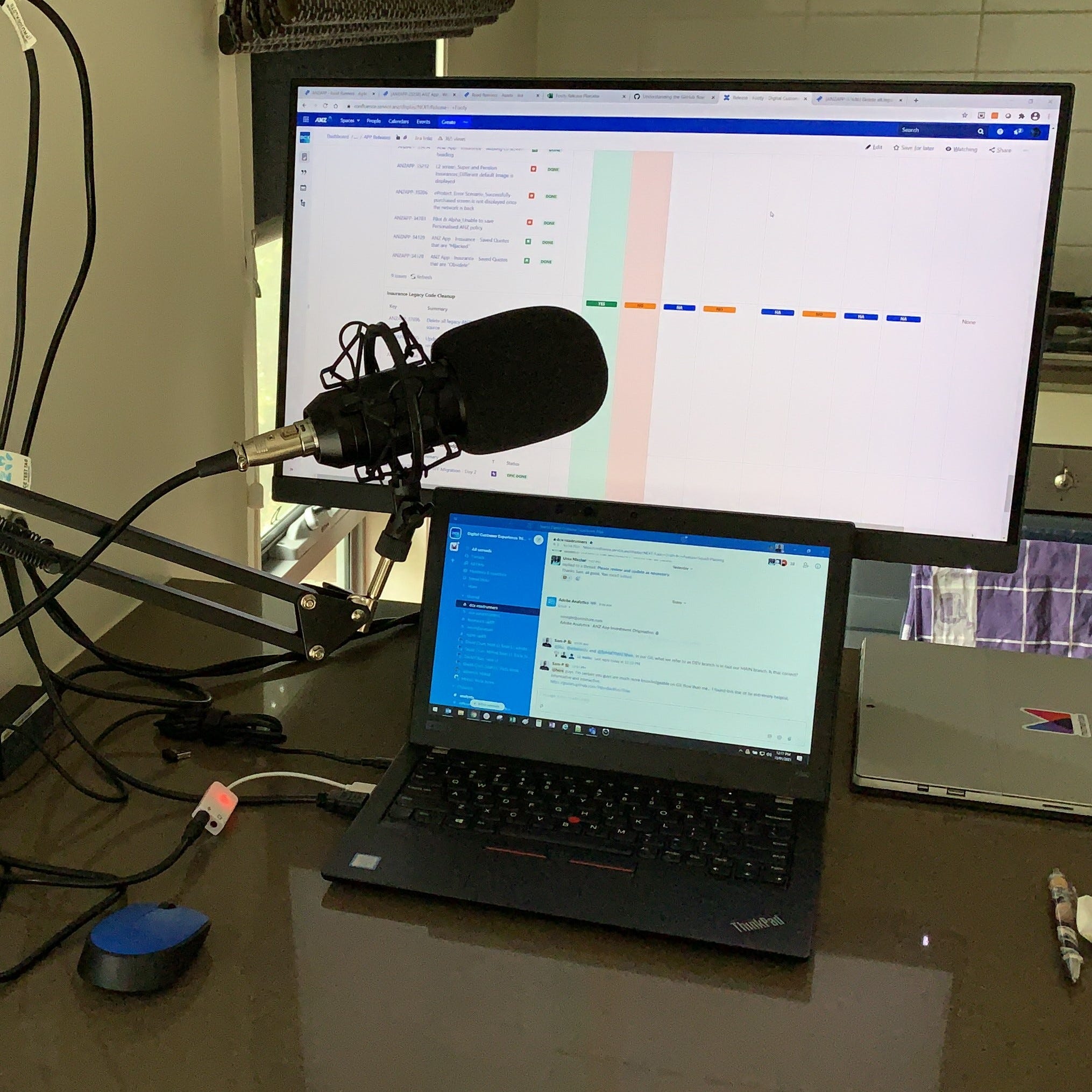 An image of a laptop with a microphone and an additional display sitting on the kitchen bench.