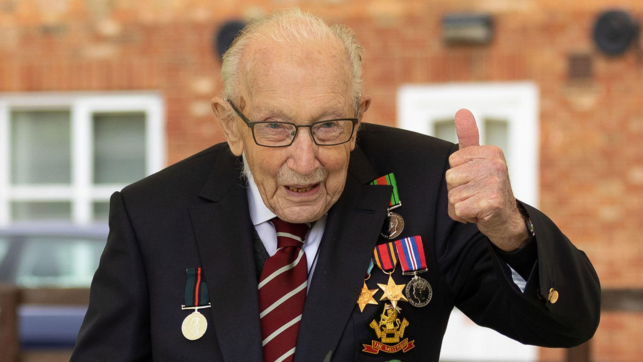 Captain Sir Tom Moore, wearing his war medals, giving a thumbs up gesture