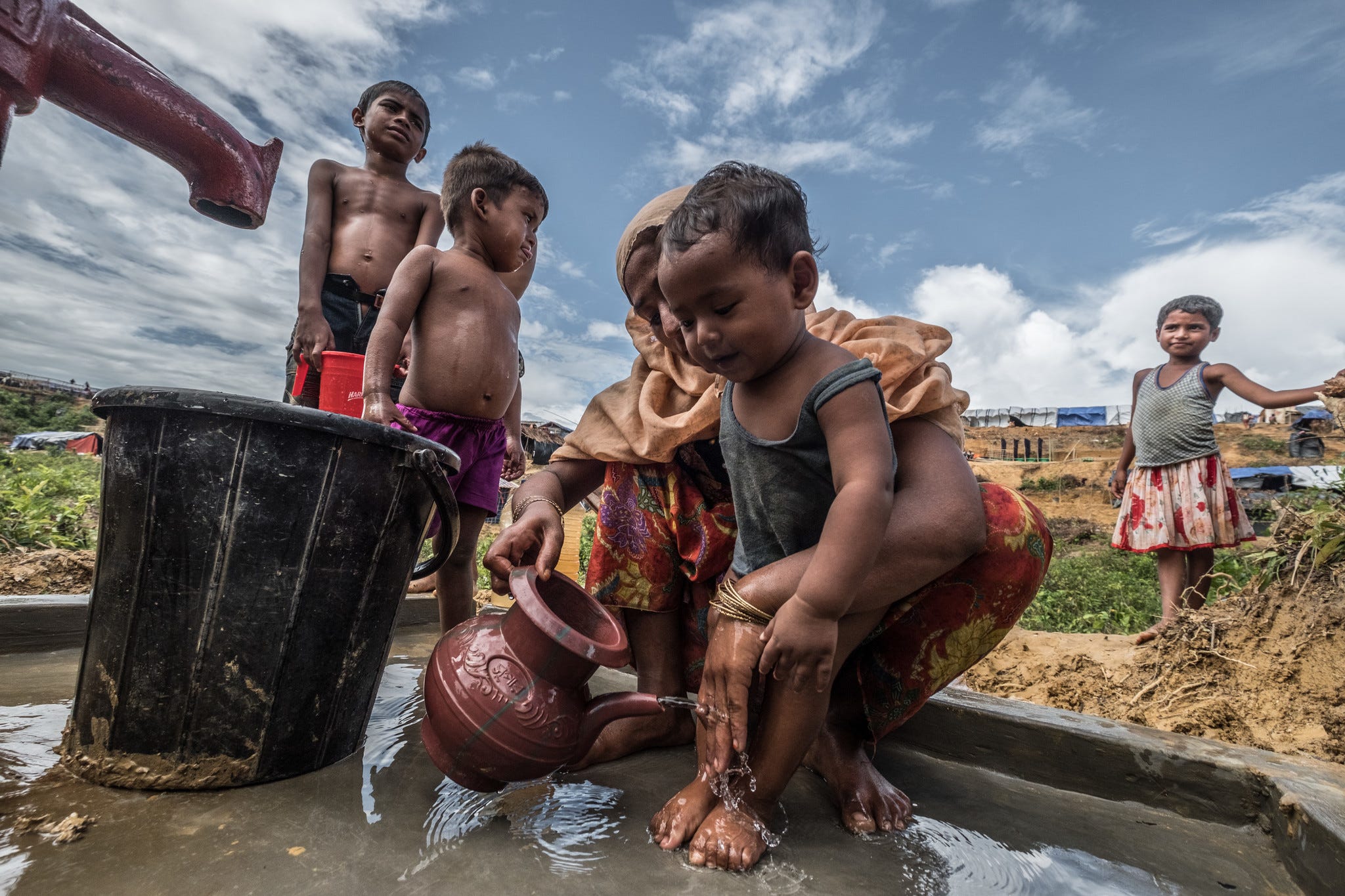 Habiba* washes her son at an Oxfam water pump. Credit: Tommy Trenchard/Oxfam