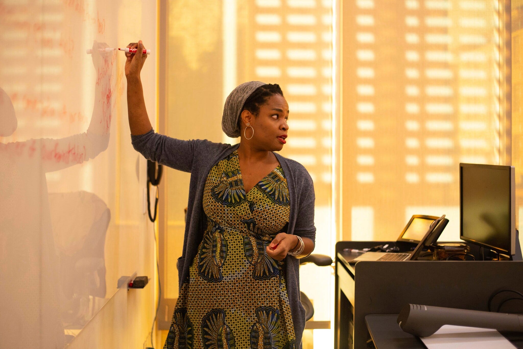 Ashley Coleman Taylor writes on a white board while turning to speak to the class.