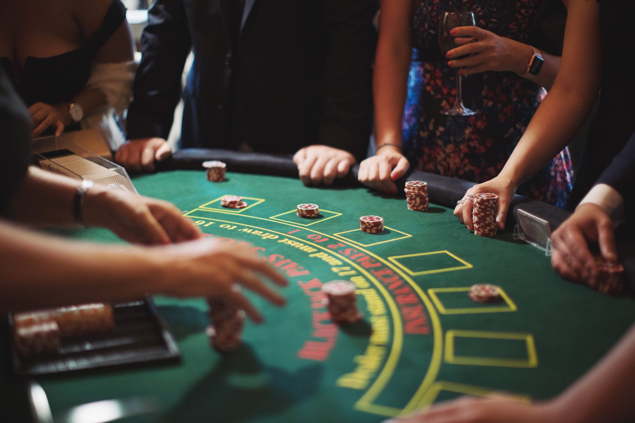 A cropped shot of a poker table and a group of people placing their bets.