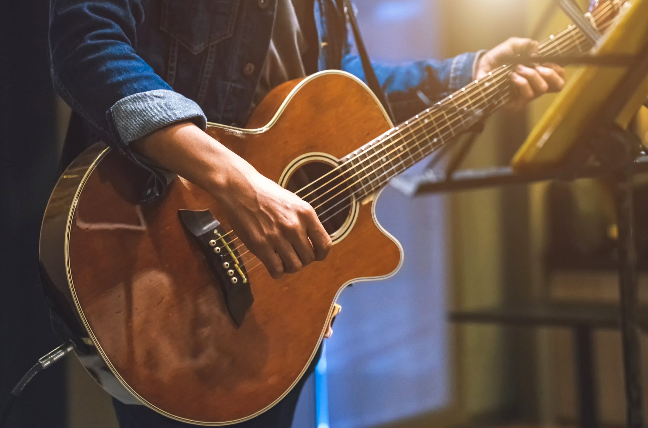 A person playing an acoustic guitar on a stage
