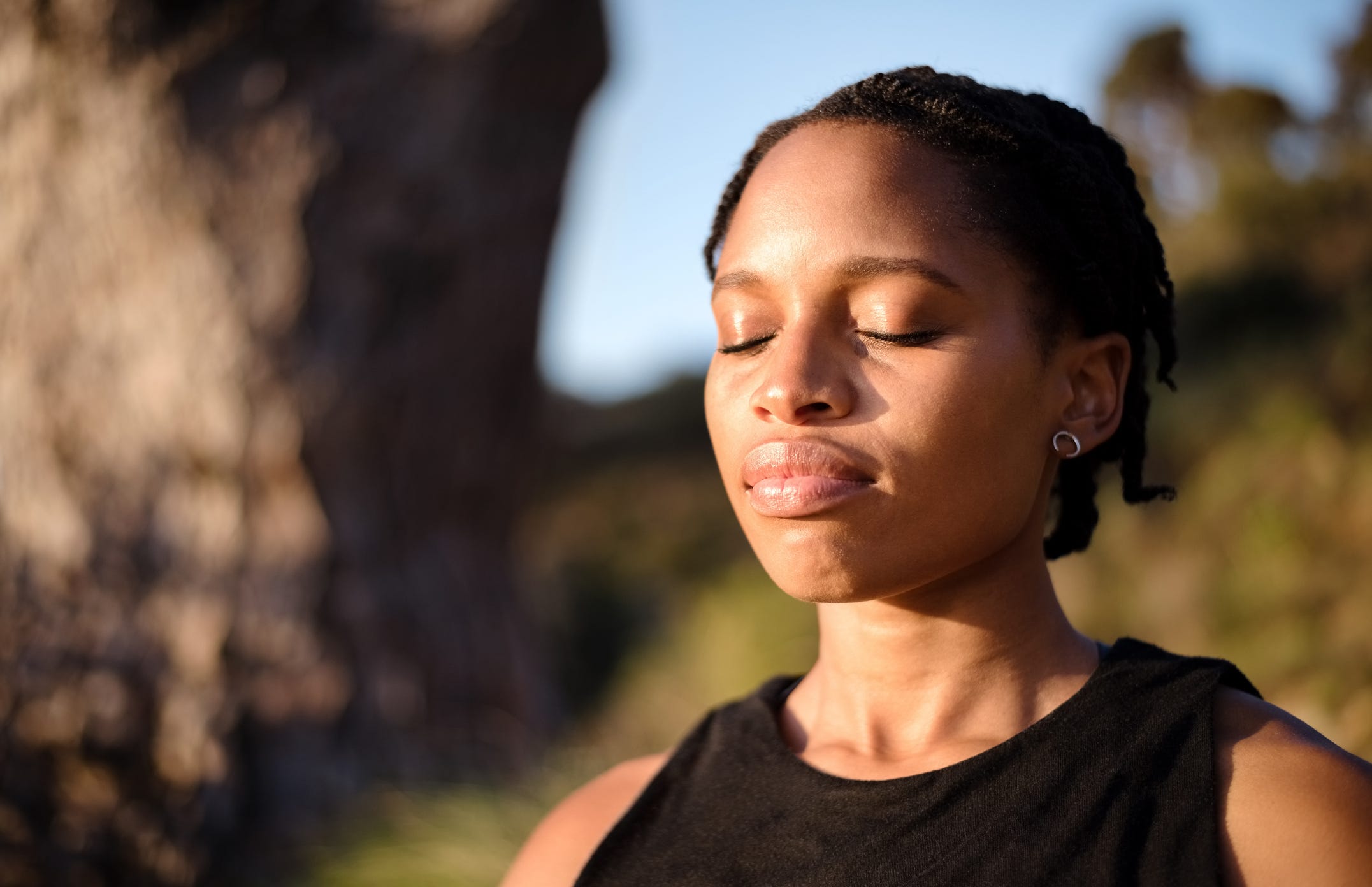Close-up shot of healthy young woman meditating outdoors with her eyes closed.